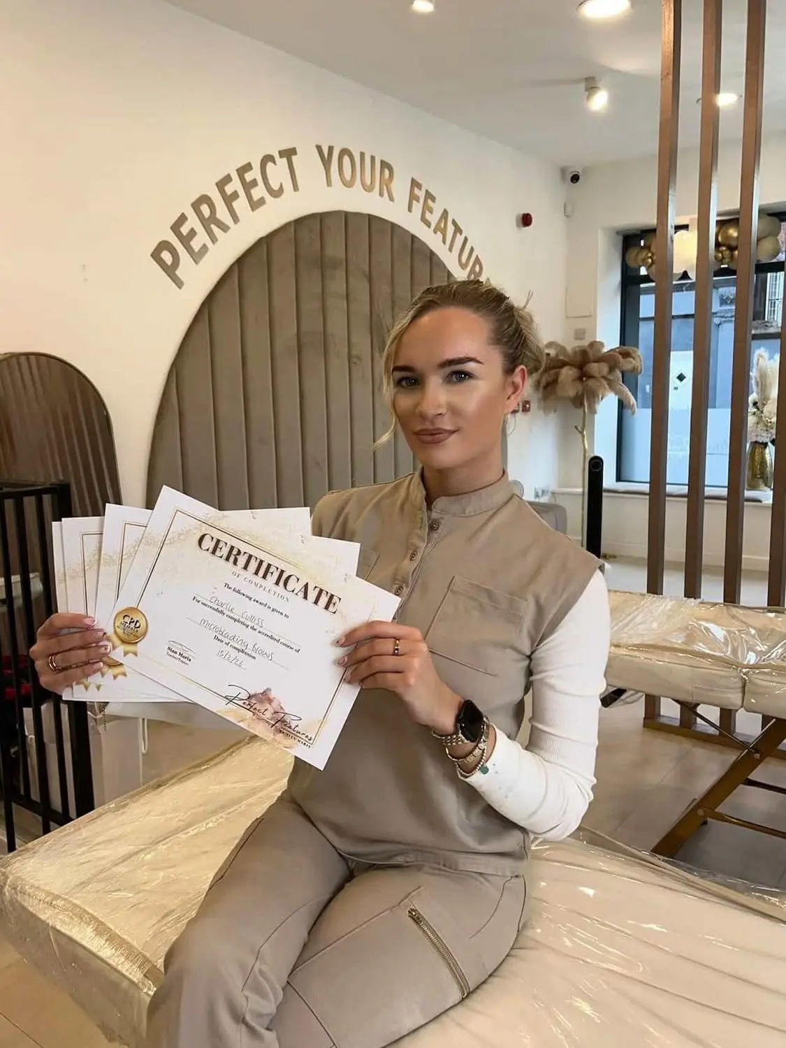Aesthetics training student holding certificates at Perfect Features Training Academy
