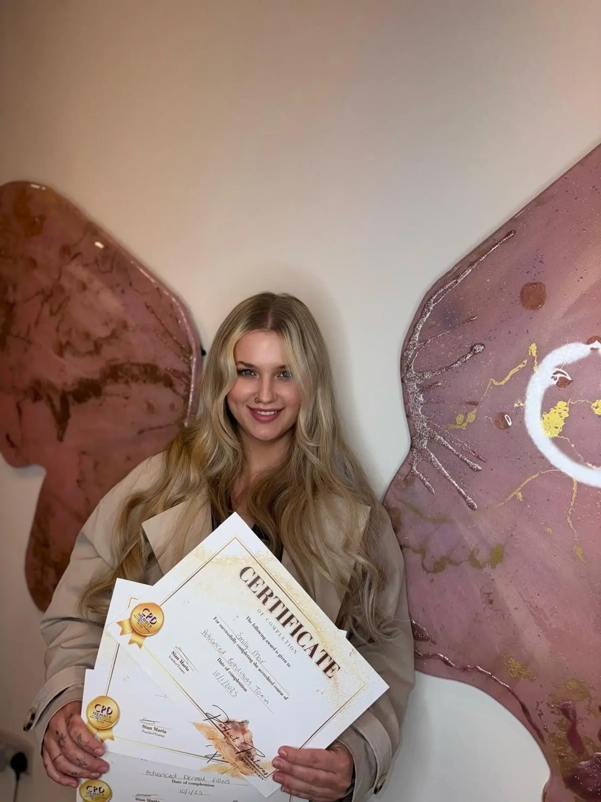 Successful aesthetics training graduate holding qualification certificates