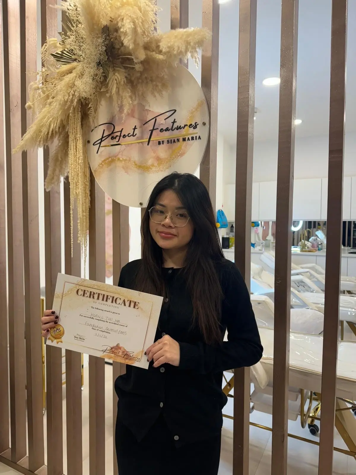 Graduate showcasing completed aesthetics training certificates at Perfect Features